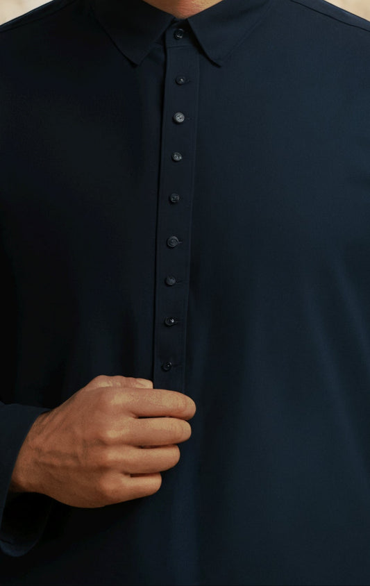 Close-up of a person wearing a black button-up shirt with a beige background