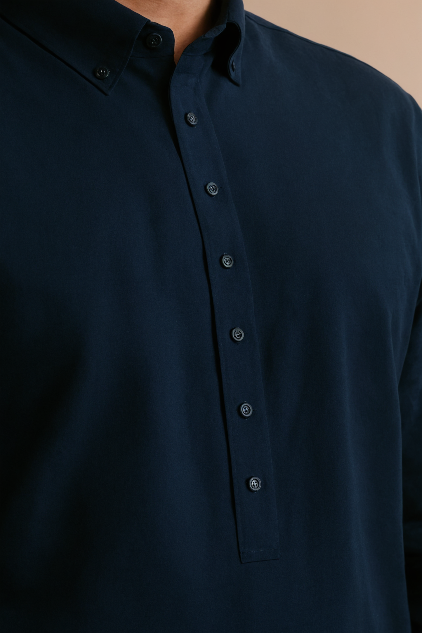 Close-up of a dark blue button-up shirt on a beige background