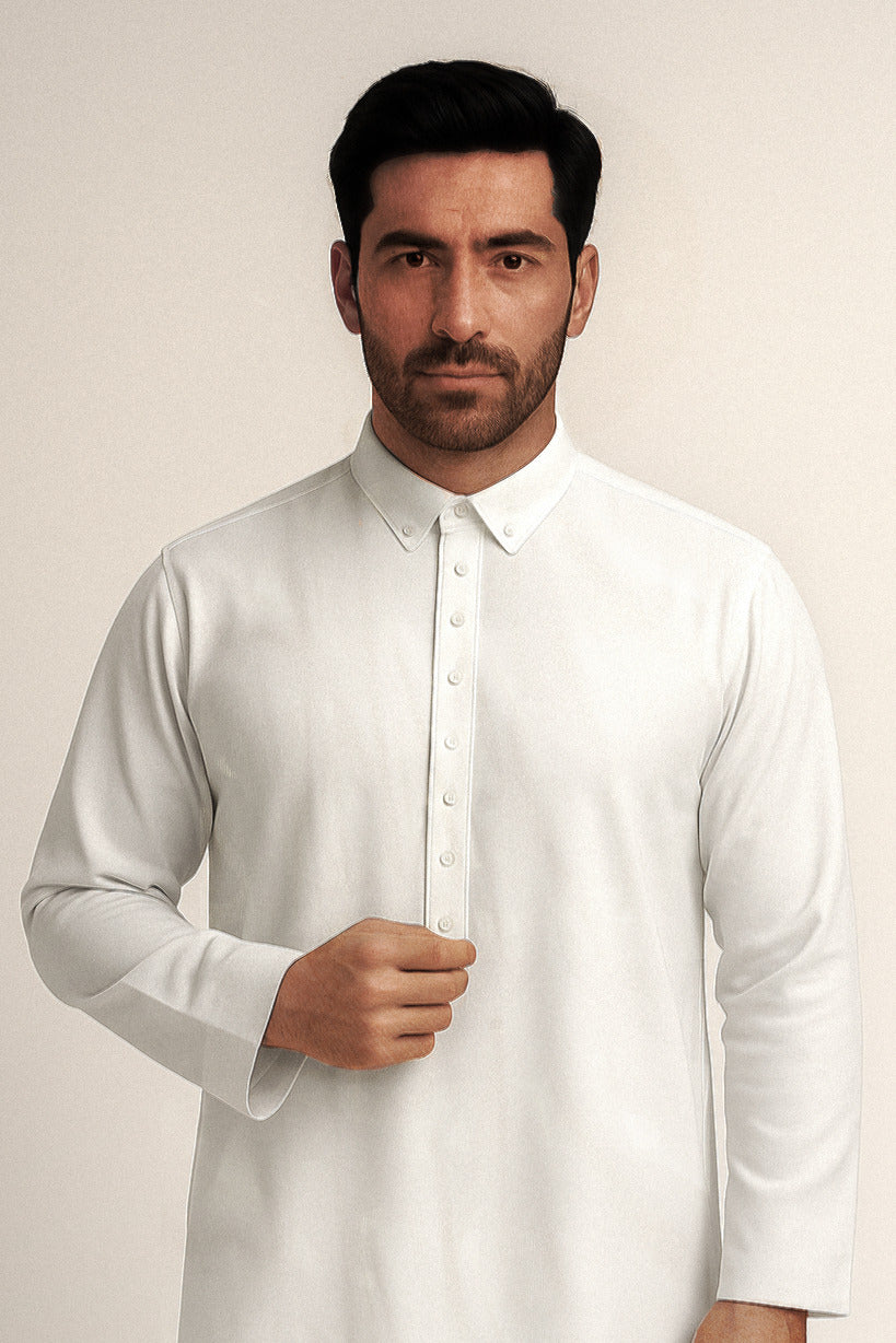 Man wearing a white Thawb against a plain background