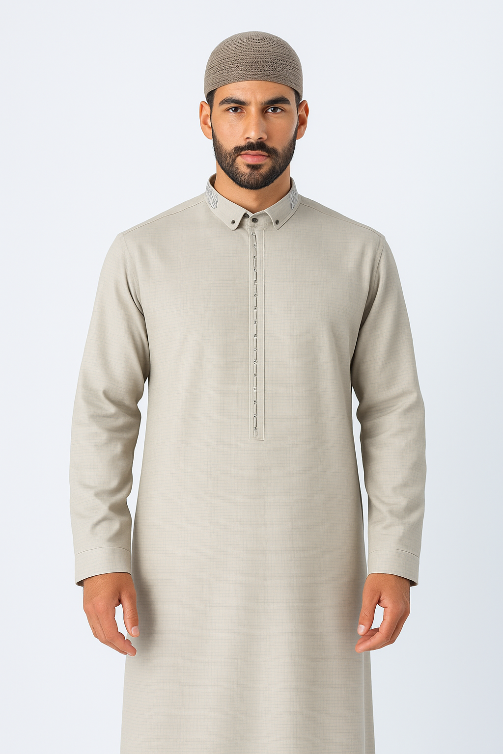 Man wearing a stone beige thobe with embroidered collar and button placket, standing against a white studio background, showcasing modest Islamic fashion.