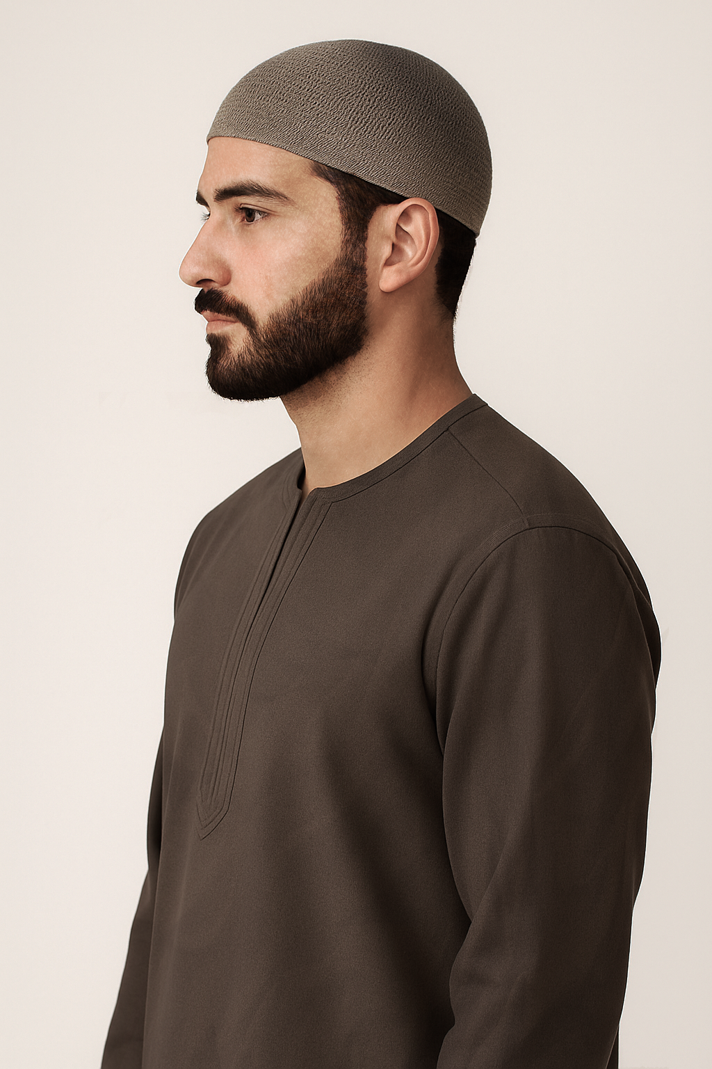 Man wearing a brown long-sleeve shirt and matching headscarf against a beige background